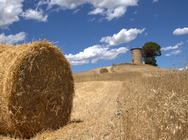 Toskanische Landschaft mit Heuballen und Steinturm