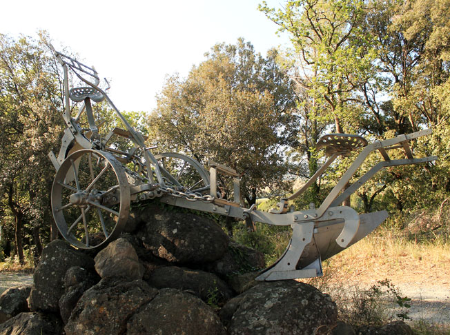 Skulptur eines historischen Pflugs in der toskanischen Landschaft