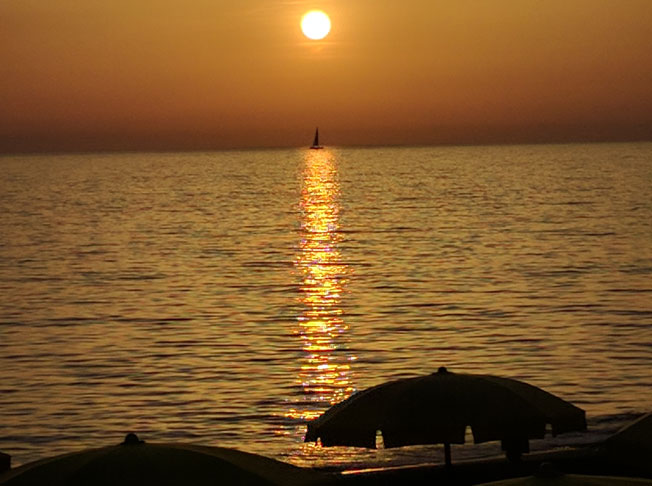 Sonnenuntergang über dem Meer mit Segelboot